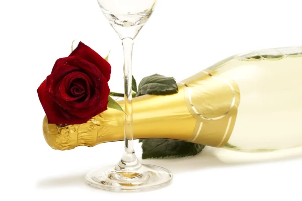 Natte rode roos op een champagnefles achter een glas champagne — Stockfoto