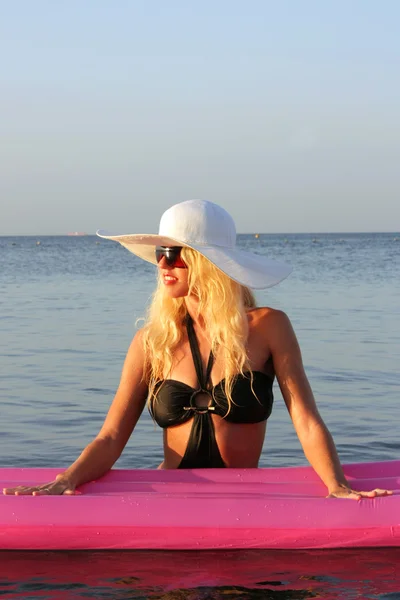 金发美女与海滩上的粉红色充气床垫 — 图库照片