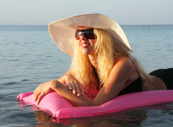 美しいブロンドの女の子ピンクの膨脹可能なマットレスで日光浴 — ストック写真