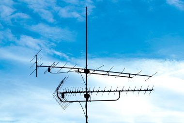 Old analog television antenna against blue sky clipart