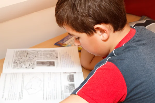 Мальчик делает домашнее задание, читает текст из книги — стоковое фото