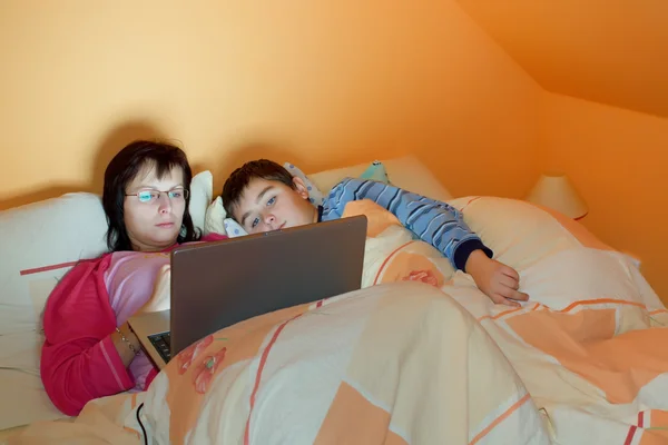 Portréja egy anya és fia használ laptop fekve az ágyon, a hom — Stock Fotó
