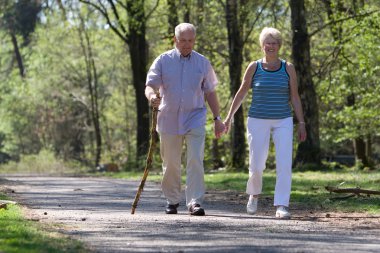Senior couple strolling through the park clipart