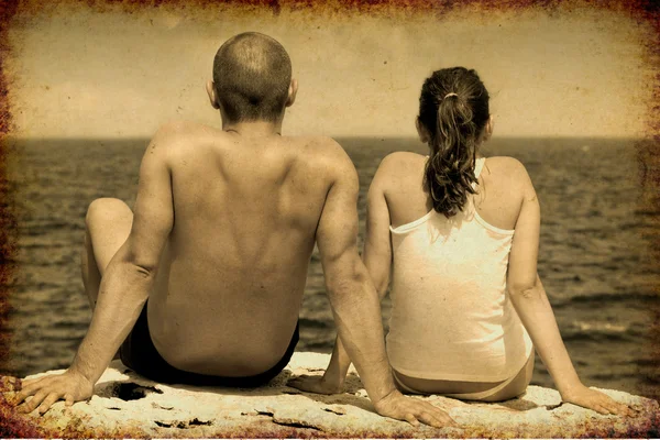 stock image Young couple sitting on a clif f and looking at sea.Vintage look in sepia