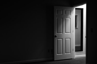 View from a dark and mysterious room with door open and light coming in from outside the room clipart