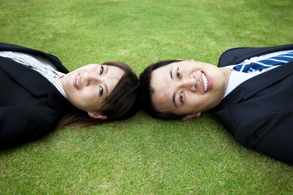 Unga vuxna par och låg i gräset — Stockfoto