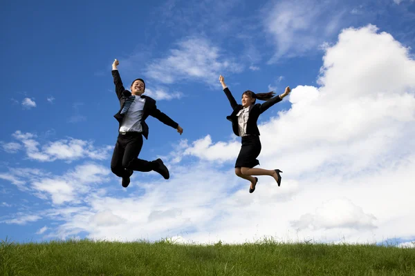 Бизнесмен и деловая женщина прыгают по зеленому лугу — стоковое фото