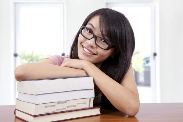 Menina sorridente bonita em uma sala de aula com livro — Fotografia de Stock