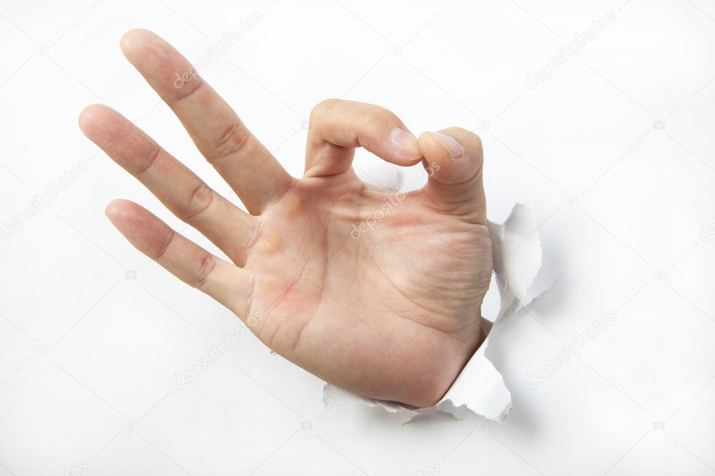 Hand punching through white paper and ok sign