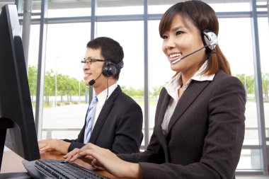 Smiling customer service representative in modern office with a headset clipart