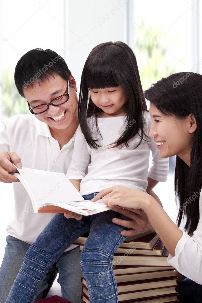 Happy asian family studing together. Parent helping daughter reading book