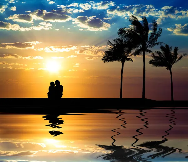 Het silhouet van het paar kijken naar zonsondergang op het strand — Stockfoto