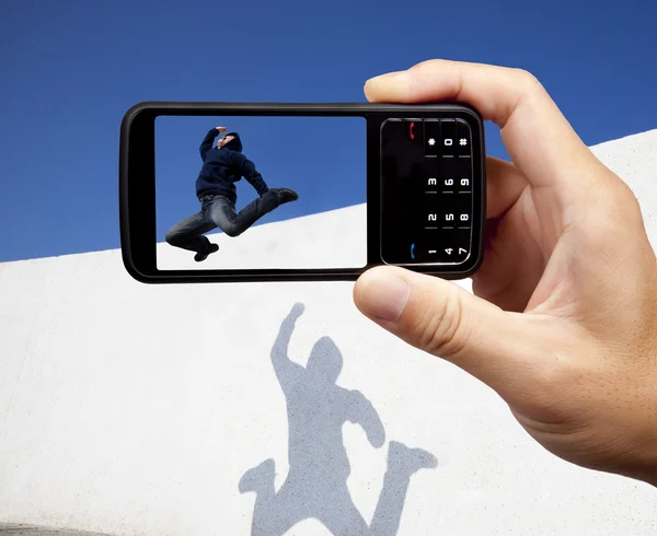 Tirando foto por telefone celular e jumper jovem — Fotografia de Stock