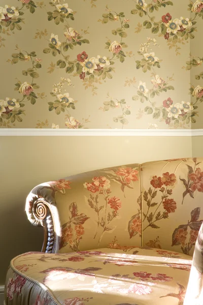 Parte da cadeira vintage com flores de pé perto da parede — Fotografia de Stock