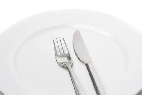 Πηρούνι και μαχαίρι σε ένα άσπρο πιάτο — Φωτογραφία Αρχείου