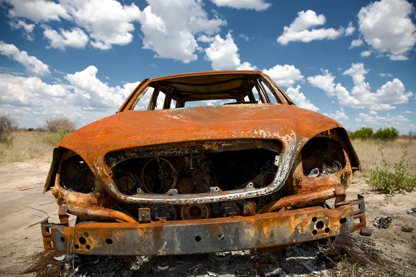 Auto abbandonata in campo sotto il cielo blu — Foto Stock