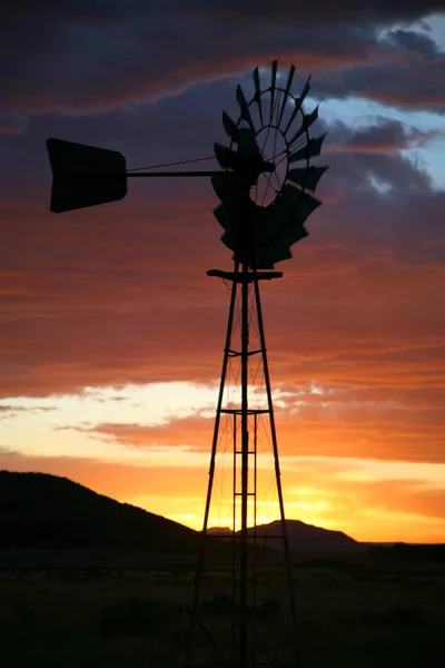 Sziluett naplementekor farm szélmalom — Stock Fotó