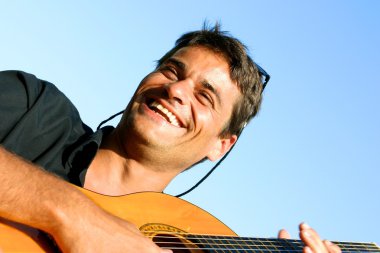 gitar çalmak ve gülümseyen sevimli genç adam