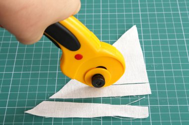 Cutting fabric with rotary cutter on a measure mat clipart