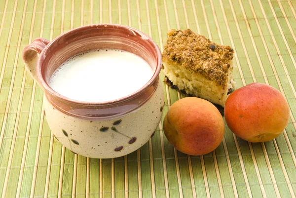 Чашка молочного торта и абрикос на коврике — стоковое фото