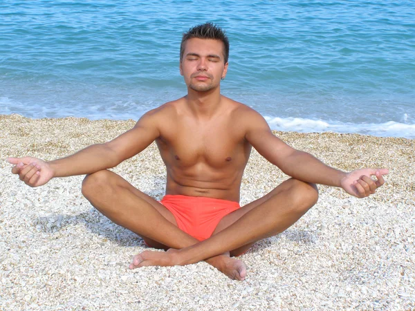 Un joven en una meditación en la playa — Foto de Stock