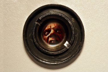 Looking through the peephole of an apartment door at an angry fellow on the other side. clipart