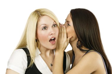 Two young females together, one whispering into the others ear. clipart