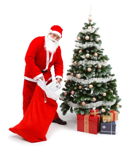 Santa claus zetten cadeaus onder de kerstboom — Stockfoto
