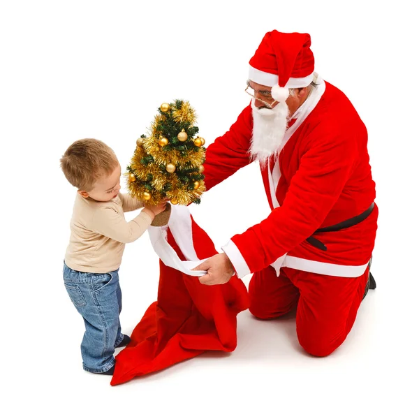 Niño pequeño pone pequeño árbol en la bolsa de Santa — Foto de Stock