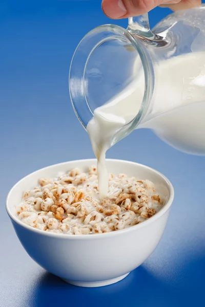 Pouring milk over wheat popped flakes — Stock Photo, Image