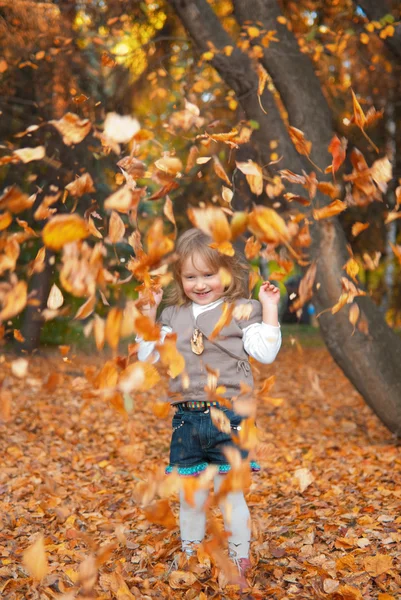 Chica está jugando con hojas de otoño — Foto de Stock