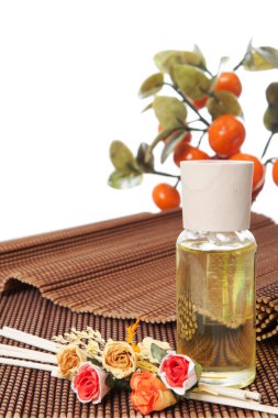 cam şişe sarı yağ ve küçük çiçekler ile kahverengi mindere yatıyordu. arka plan, taş ağaçlar