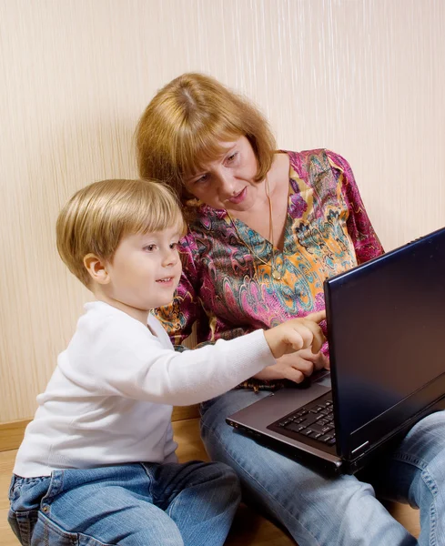 stock image Mother and her son siting on a floor looking the laptop