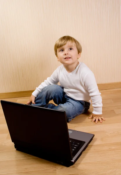 stock image The child on the wood floor with laptop