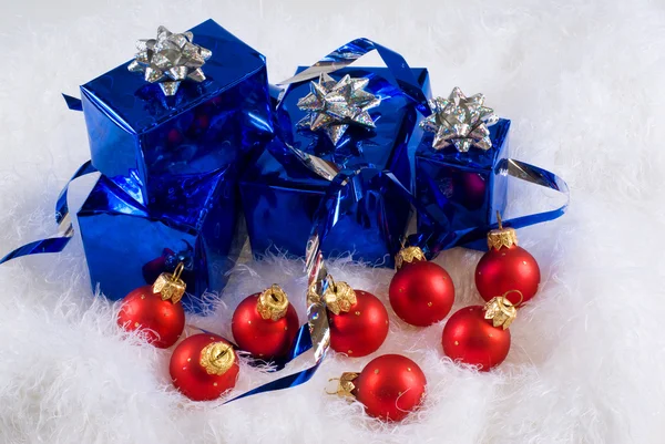 Blue boxes and Christmas red balls on the white skin — Stock Photo, Image