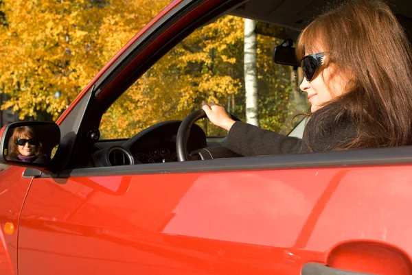 La chica en el coche rojo y su reflejo en un espejo —  Fotos de Stock