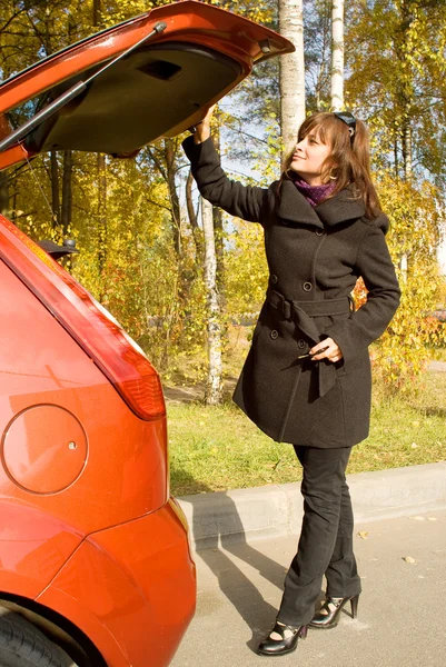 A menina fecha um lugar de bagagem do carro vermelho — Fotografia de Stock