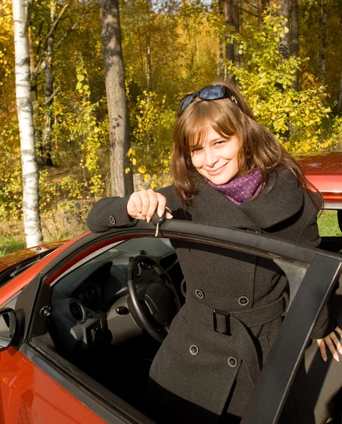 Dziewczyna z kluczem pozostawia czerwony samochód — Zdjęcie stockowe