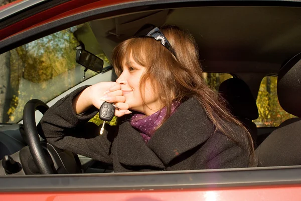 Unga kvinnor med nyckel i kabinen på hennes röda bil — Stockfoto