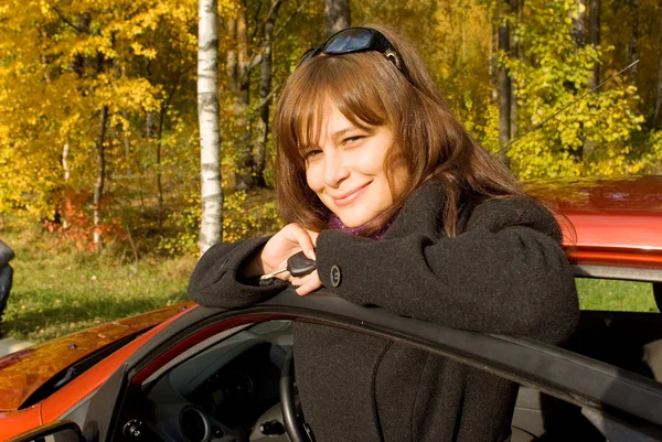 Młodych kobiet z kluczem w pobliżu jej czerwony samochód — Zdjęcie stockowe