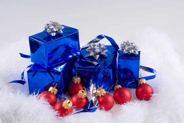 Blue boxes and Christmas red balls are on the white fur — Stock Photo, Image