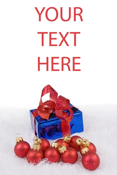 Cartão de Natal com esferas vermelhas e caixa azul na pele branca — Fotografia de Stock