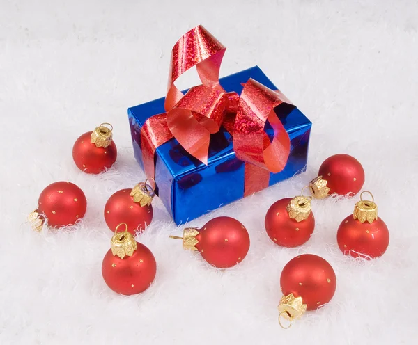 Rode bollen en blauwe doos met rode strik op de witte — Stockfoto