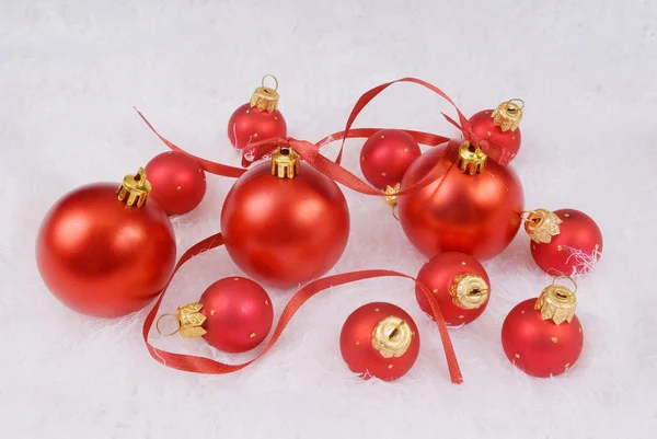 Red spheres with red ribbon on the white fur — Stock Photo, Image