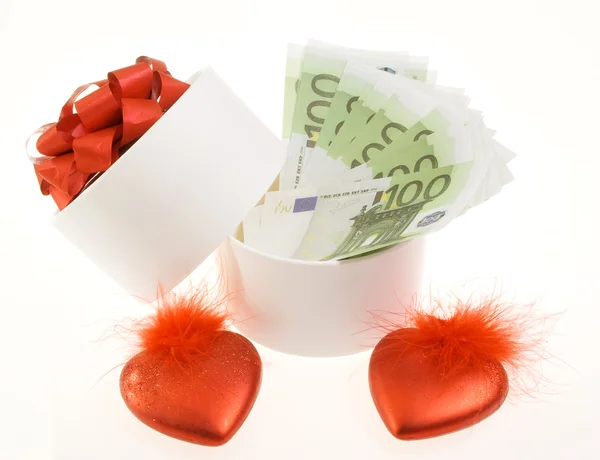 Caja redonda blanca con billetes y dos corazones rojos — Foto de Stock