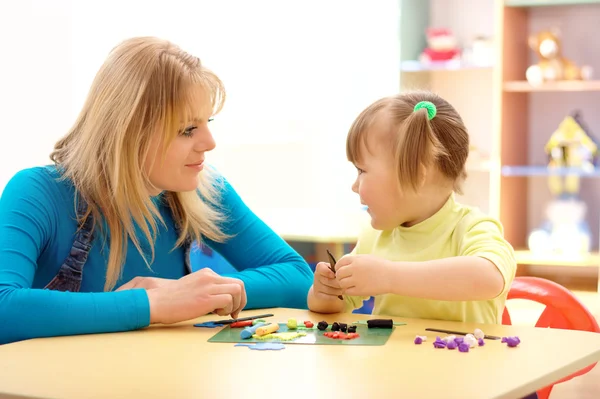 Lehrerin und kleines Mädchen spielen mit Knetmasse — Stockfoto