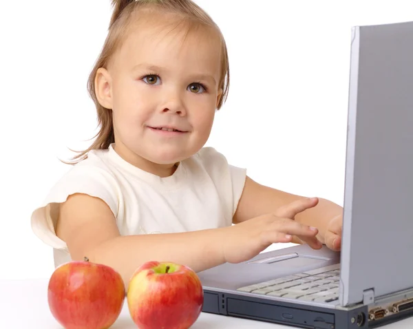 Niedliches kleines Mädchen mit Laptop und zwei Äpfeln — Stockfoto