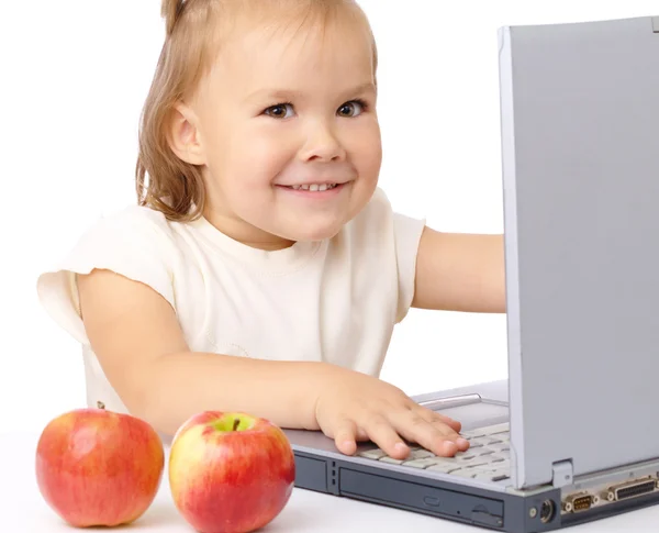 Menina feliz bonito com laptop e duas maçãs — Fotografia de Stock