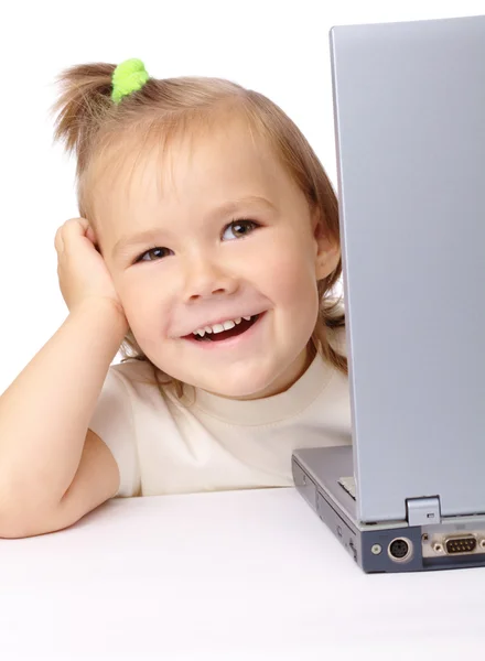 Schattig klein meisje is op zoek vanuit haar laptop — Stockfoto