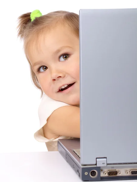 Милая маленькая девочка смотрит из своего ноутбука — стоковое фото